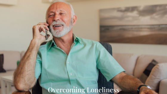 An older man smiling while talking on the telephone, fostering connection and avoiding social isolation.