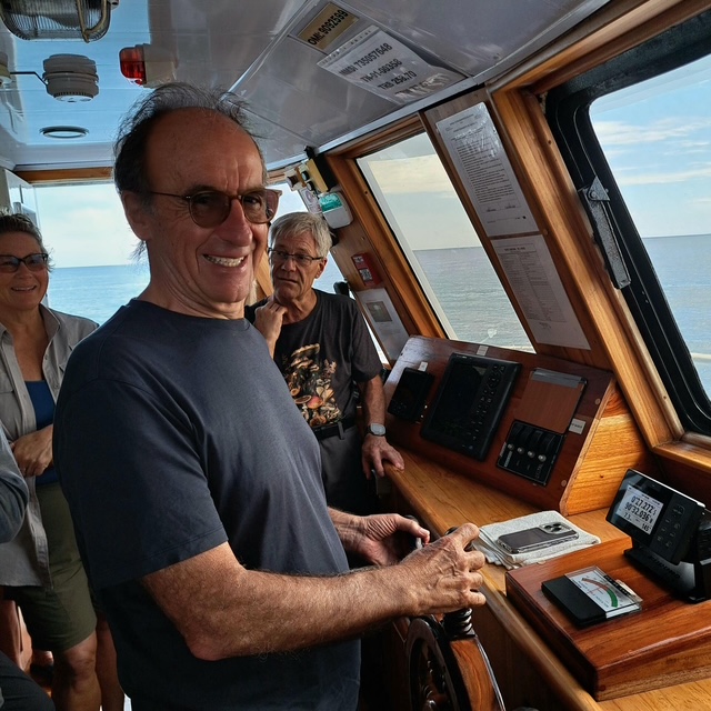 Dr. Joseph Casciani at the helm of a boat in the Galápagos Islands, embracing adventure and lifelong exploration.